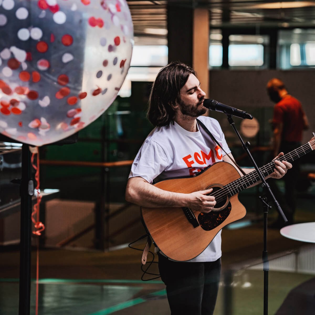 Dusty Lee Stephenson singing and playing guitar to the audience at a FOMO Fridays event