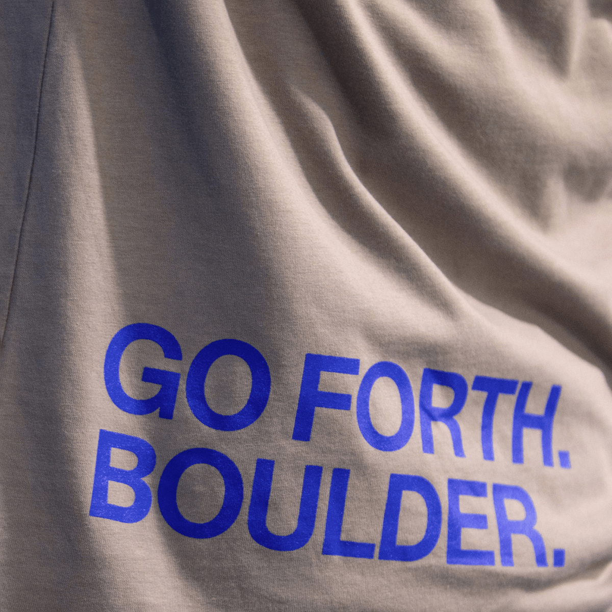 Blue words printed on fabric that read 'Go forth and boulder'