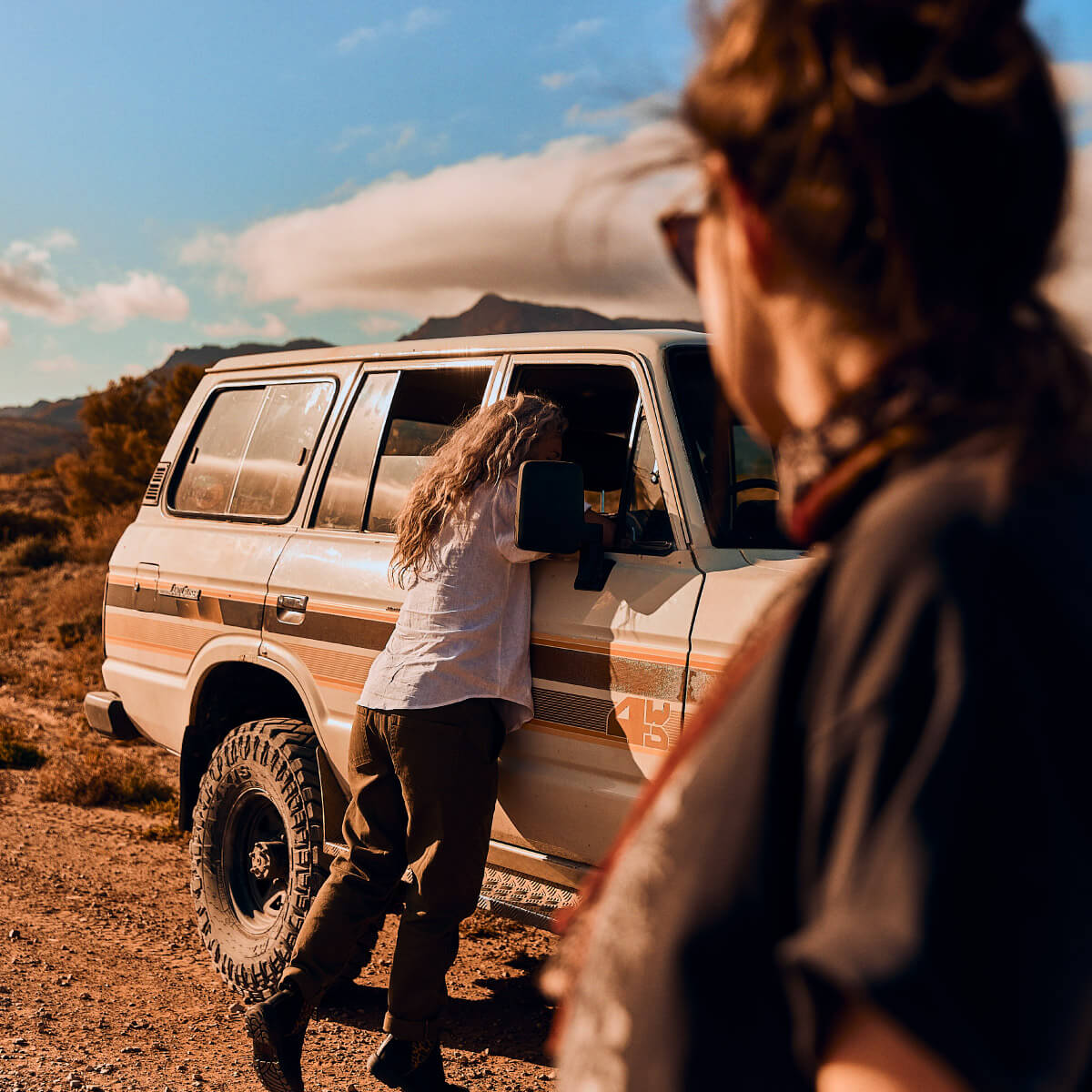 Two women on the road together in an old dusty 4-wheel drive.