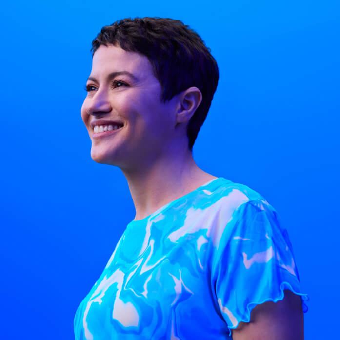 A short-haired woman photographed in studio with a coloured background